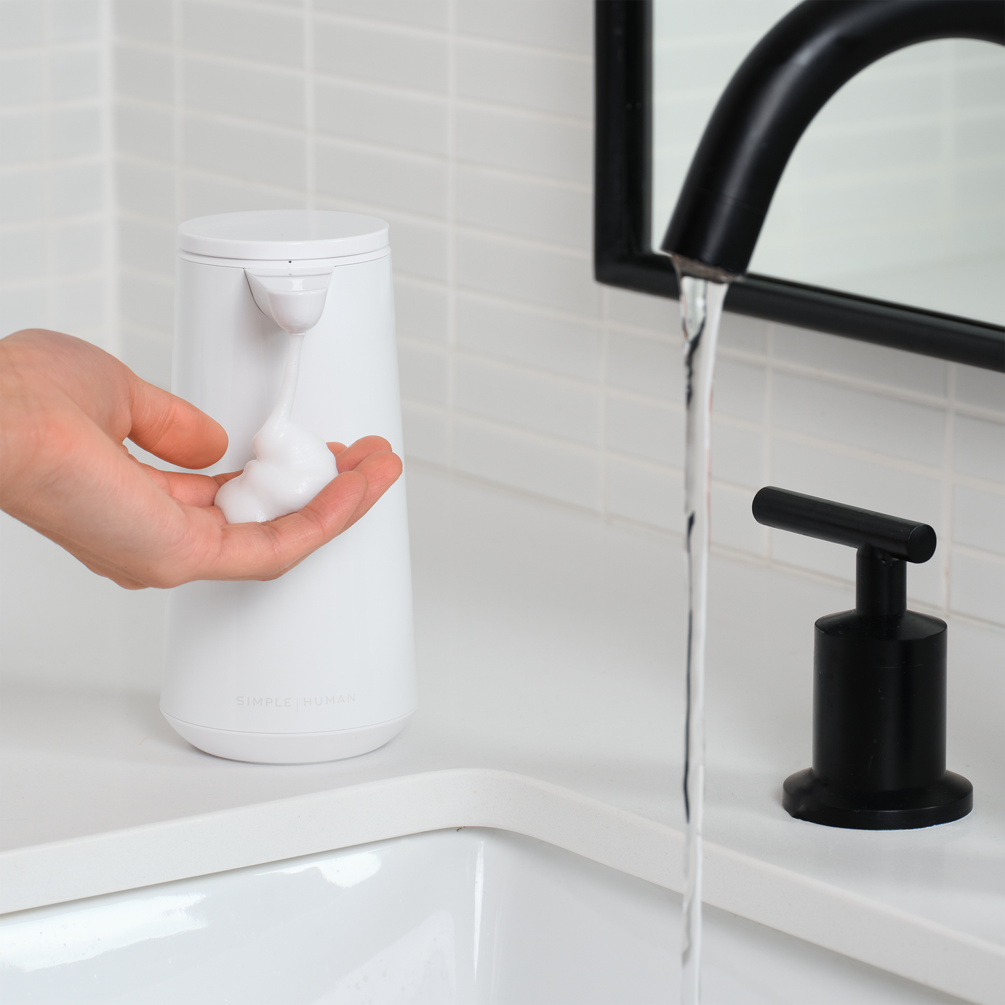 Simplehuman White Sensor Pump Foam dispensing foam into a hand by a modern sink, touch-free operation.